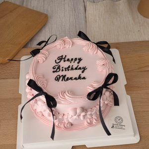 Blush pink vintage birthday cake with buttercream piping and black ribbon bows