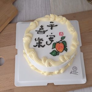 Longevity peach birthday cake with Chinese calligraphy and hand-piped buttercream border