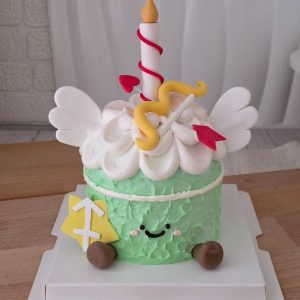 Sagittarius Horoscope Jellycat Style Birthday Cake with sage green textured cream, smiling character face, angel wings, cupid arrow topper, candle topper, and Sagittarius zodiac symbol by The Cake Alchemy Puchong Selangor