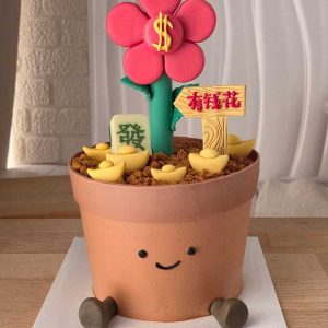 Jellycat-style flower pot cake with a smiling face, money flower topper, gold ingots, and prosperity-themed decorations by The Cake Alchemy in Puchong Selangor Malaysia.