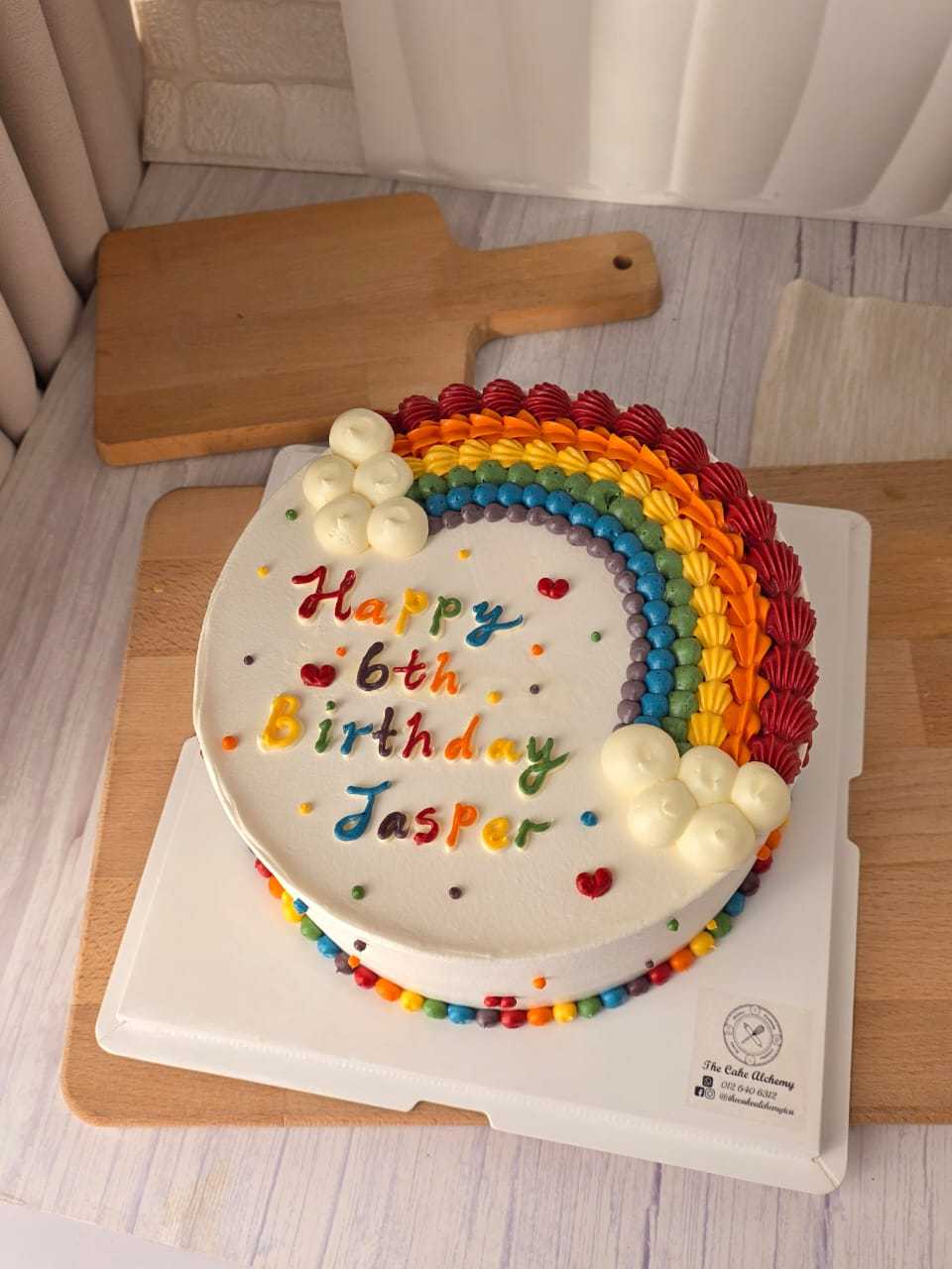 Colorful rainbow birthday cake with hand-piped rainbow decoration, fluffy cloud details, and personalized birthday message by The Cake Alchemy in Puchong Selangor Malaysia.