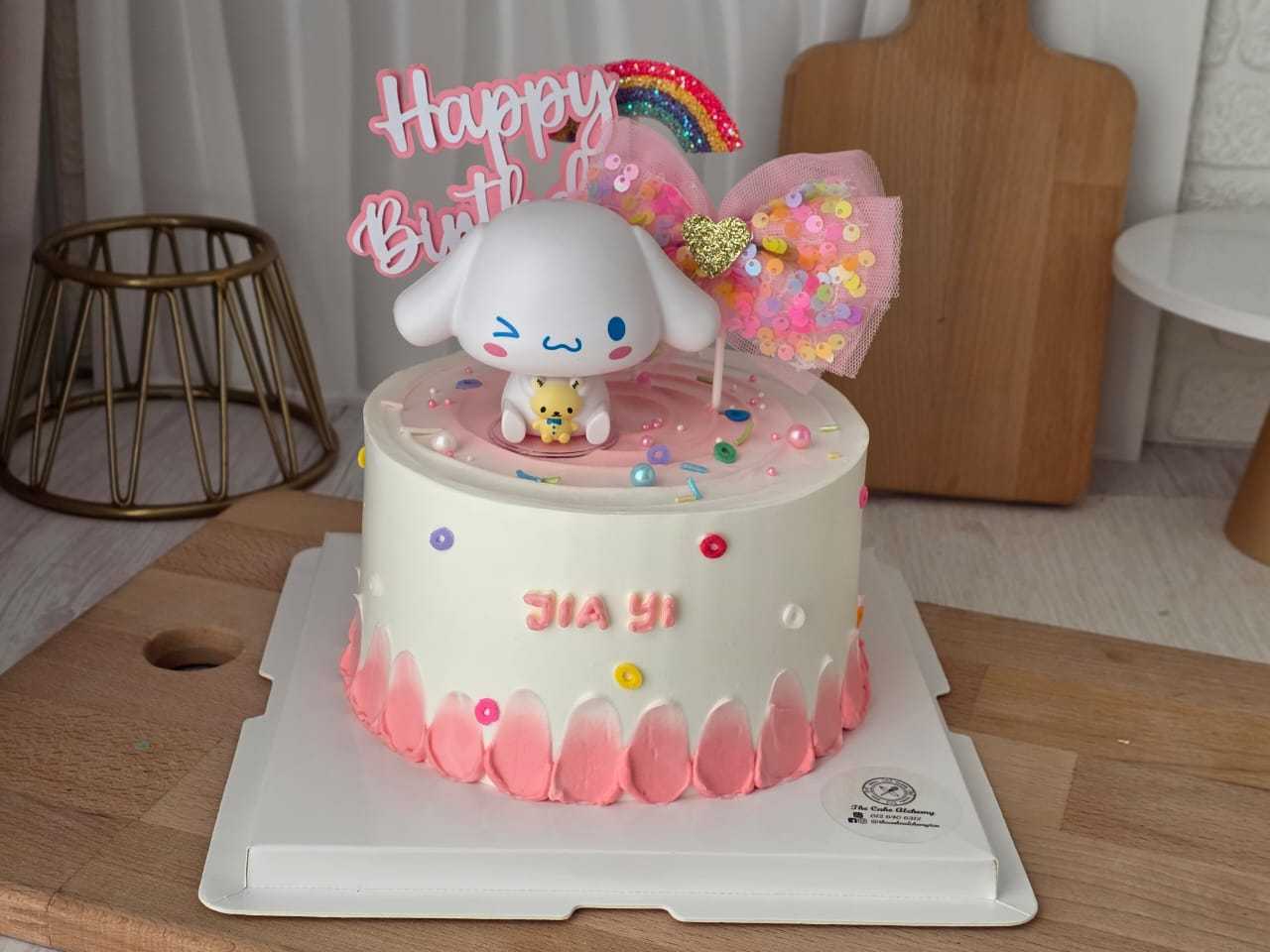 Cinnamoroll birthday cake with pastel pink cream, Sanrio character topper, rainbow decoration, and personalized name by The Cake Alchemy in Puchong Selangor Malaysia.