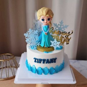 Elsa Frozen birthday cake with princess topper, snowflakes, castle decorations, blue cream accents, and personalized name by The Cake Alchemy in Puchong Selangor Malaysia.
