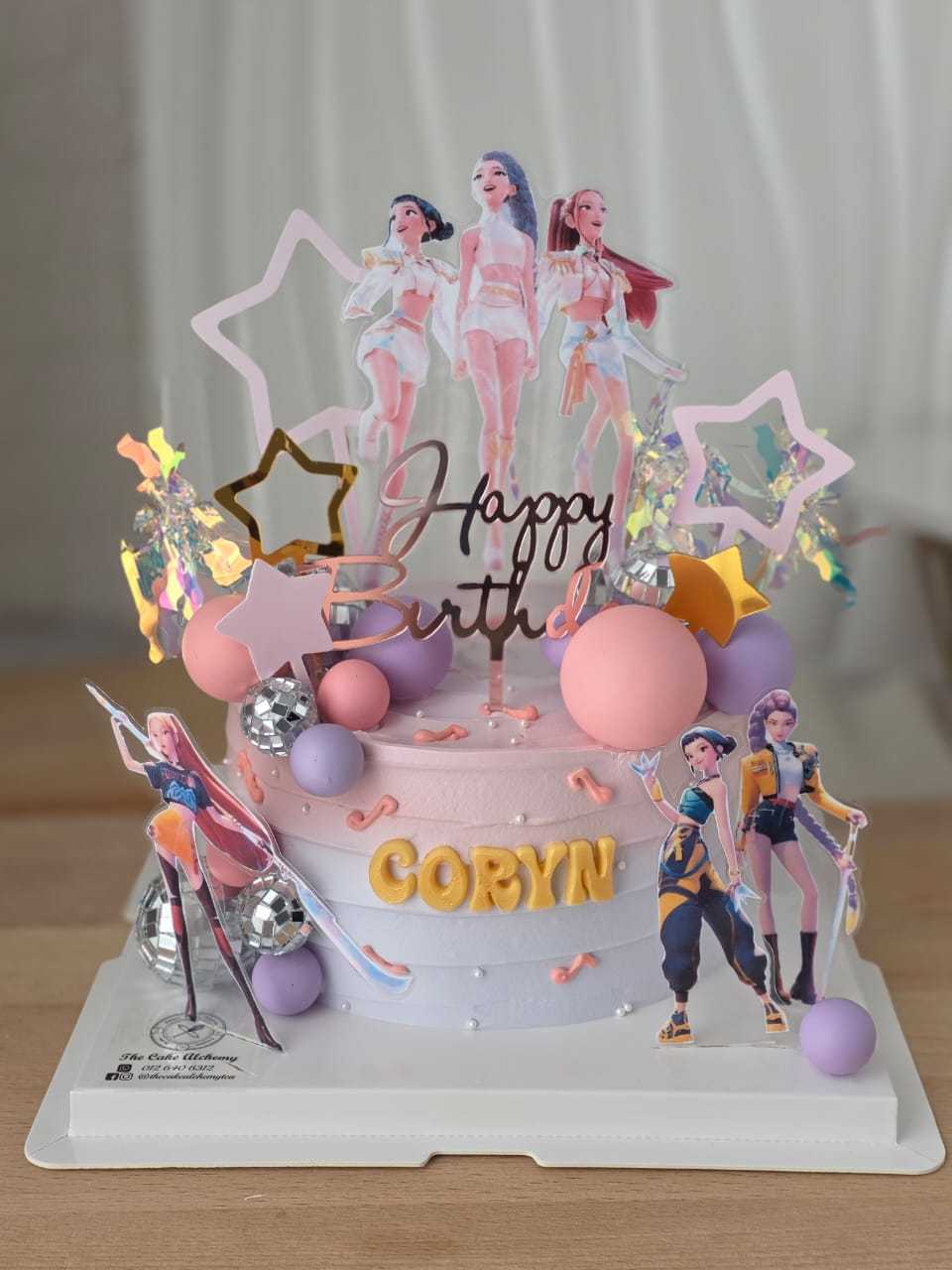 Huntrix themed birthday cake with pastel pink and lavender frosting, character toppers, holographic decorations, and personalized name by The Cake Alchemy in Puchong Selangor Malaysia.