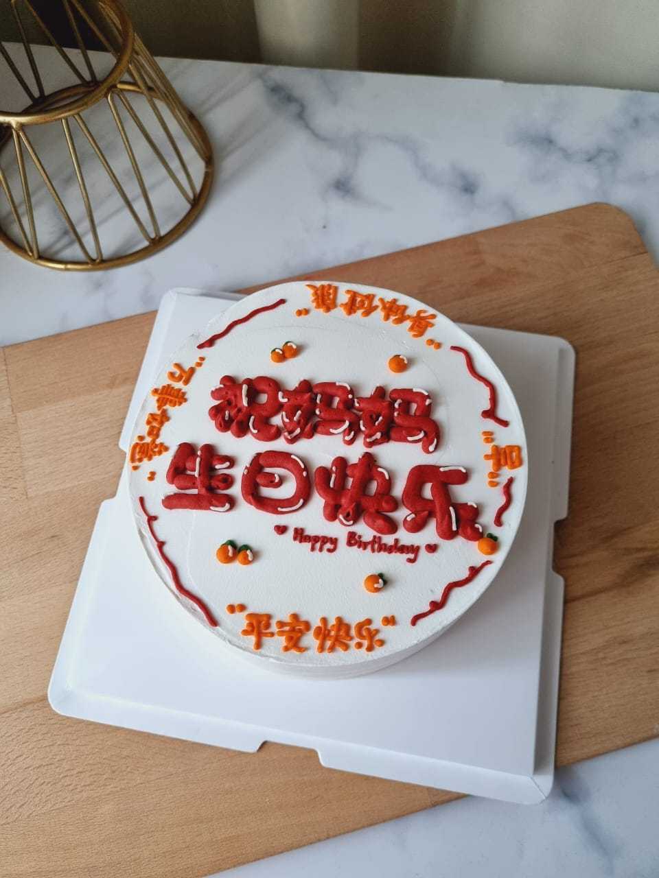 Minimalist Chinese birthday cake with hand-piped Chinese birthday wishes, red and orange cream lettering, and small mandarin orange decorations by The Cake Alchemy in Puchong Selangor Malaysia.