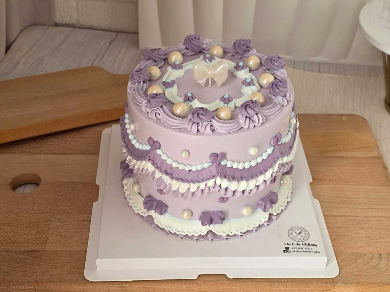 Purple vintage Lambeth birthday cake with elegant lavender cream piping, pearl decorations, ribbon details, and a white bow topper by The Cake Alchemy in Puchong Selangor Malaysia.