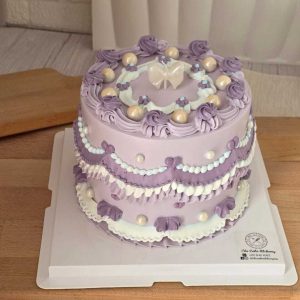 Purple vintage Lambeth birthday cake with elegant lavender cream piping, pearl decorations, ribbon details, and a white bow topper by The Cake Alchemy in Puchong Selangor Malaysia.