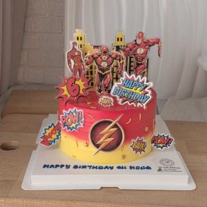The Flash superhero birthday cake with comic-style toppers, red and yellow cream, city skyline backdrop, and personalized birthday message by The Cake Alchemy in Puchong Selangor Malaysia.