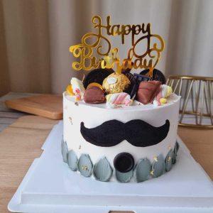 Moustache Dad birthday cake with chocolates, cookies, gold accents and Happy Birthday topper by The Cake Alchemy